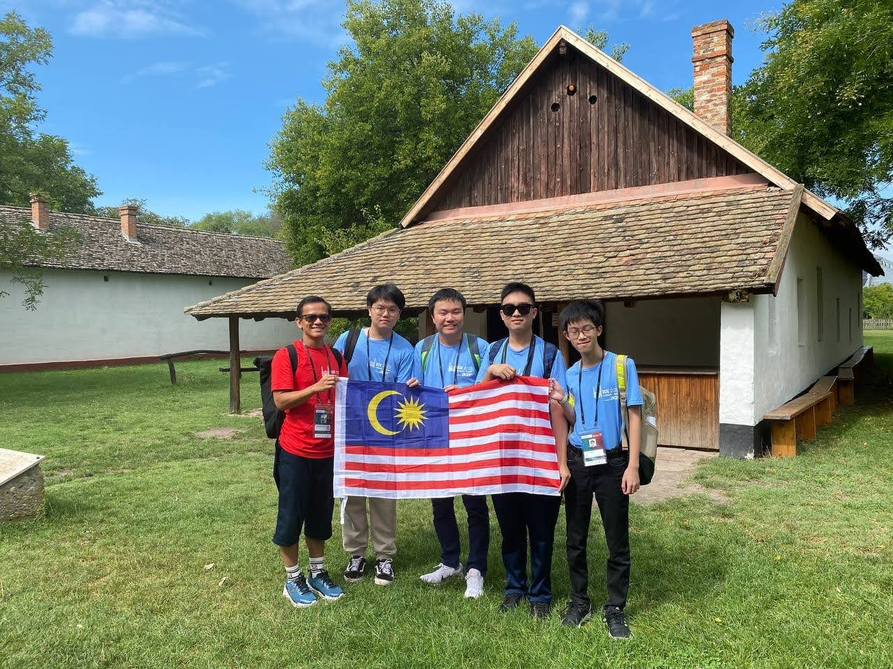 Group photo in front of a hut. Happy Malaysia Day!
